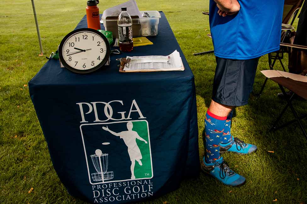 A disc golf tournament register table with a clock on it